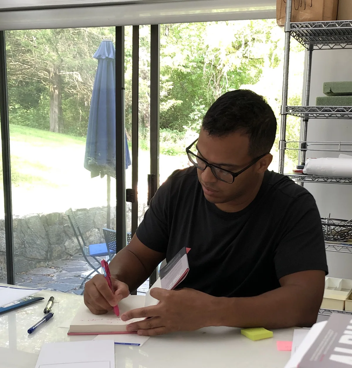 Robert Solano writing at a table by a window